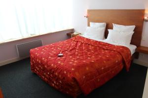 a bedroom with a large bed with a red comforter at Hôtel Restaurant Logis La Palette in Wettolsheim