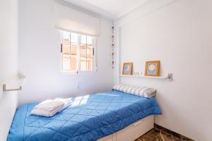 um quarto com uma cama com lençóis azuis e uma janela em Puerto Arrecife em Santa Pola