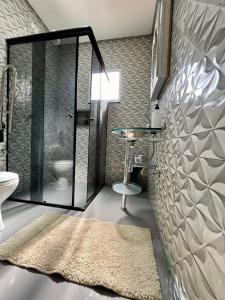 a bathroom with a glass shower and a rug at A Cozy Little House in a Beautiful Property in Brasilia