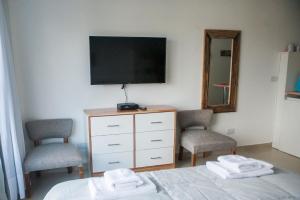 1 dormitorio con 1 cama, 2 sillas y TV en Gente del Sur - Lugones en Ushuaia