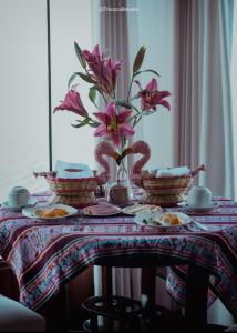 einen Tisch mit rosa Blumen in einer Vase darauf in der Unterkunft Urus Beluxia in Puno