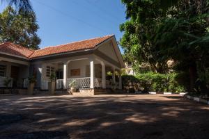 una casa con porche y árboles en un patio en Green Square Grove - Entire House, en Kampala