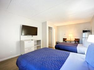 a hotel room with two beds and a flat screen tv at Stayable Jacksonville North in Jacksonville