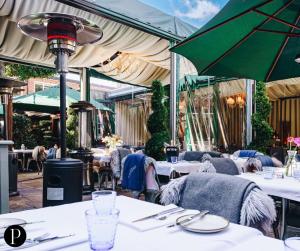 un restaurante con mesas blancas y sombrillas verdes en Purchases Restaurant & Accommodation, en Chichester