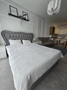 a large white bed in a bedroom with a couch at Caesar Blue Resort Studio with Sea View in Trikomo +15 photos