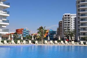 a swimming pool with chaise lounges and chairs and buildings at Caesar Blue Resort Studio with Sea View in Trikomo