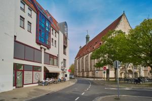 a city street with buildings and people sitting on a sidewalk at City-Deluxe in Braunschweig in Braunschweig