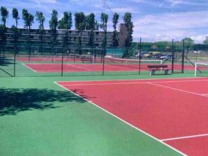 a tennis court with two tables and a bench on it at Lovely Acacia in De Haan