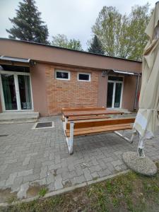 un banco de madera sentado frente a un edificio en Öreg-tó Youth Hostel en Tata