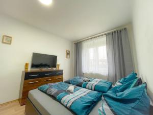 a bedroom with a bed with blue sheets and a television at Moderne Ferienwohnung Felbbauer #30 in Knittelfeld