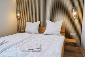 1 cama con sábanas blancas y almohadas en una habitación en City-Deluxe in Braunschweig, en Brunswick