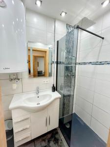 La salle de bains blanche est pourvue d'un lavabo et d'une douche. dans l'établissement Moderne Ferienwohnung Felbbauer #30, à Knittelfeld