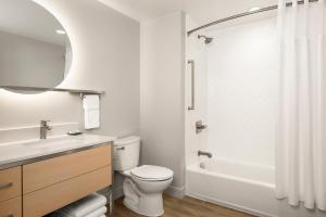 a white bathroom with a toilet and a bath tub at TownePlace Suites by Marriott Iron Mountain in Iron Mountain