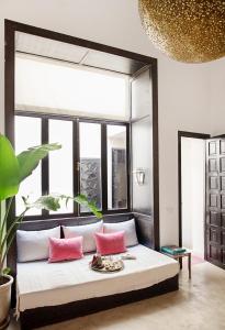 uma cama com almofadas cor-de-rosa num quarto com uma janela em P´tit Habibi em Marrakech