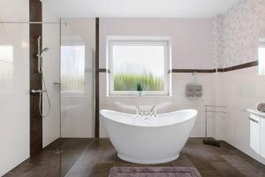 a white bathroom with a tub and a window at Haus Eiderblick in Horst +22 photos