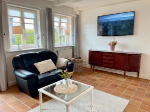 a living room with a black leather couch and a tv at Landhaus Tons 2 Jan in Keitum