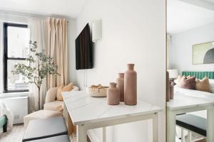 ein Wohnzimmer mit einem weißen Tisch mit Vasen darauf in der Unterkunft 73-919 New Studio UWS Doorman Gym in New York