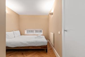 um pequeno quarto com uma cama e uma janela em GuestReady - Beige barley near The British Museum em Londres