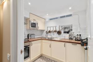 a kitchen with white cabinets and stainless steel appliances at GuestReady - Beige barley near The British Museum in London