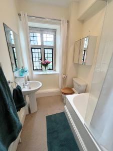 a bathroom with a tub and a toilet and a sink at Parsonage House, Badminton in Great Badminton