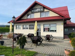 a group of chairs and umbrellas in front of a building at Zajazd Sinmar in Maniowy