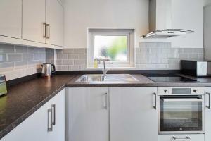 a kitchen with white cabinets and a sink and a window at Host & Stay - Rose Cottage in Thropton +12 photos
