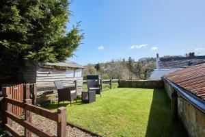 a yard with chairs and a fence and a house at Host & Stay - Rose Cottage in Thropton