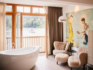 a bathroom with a tub and a large window at Seehotel Grundlsee in Grundlsee