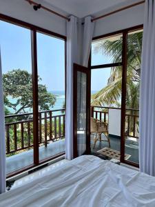 a bedroom with a bed and a view of the ocean at Coconut Palm beach restaurant and rooms in Dickwella