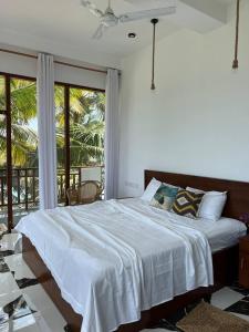 a bedroom with a white bed and a balcony at Coconut Palm beach restaurant and rooms in Dickwella
