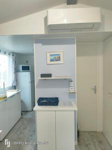La cuisine est équipée de placards blancs et d'un réfrigérateur blanc. dans l'établissement Camping Soleiluna, à Rocbaron