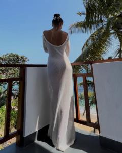 Una mujer con un vestido blanco mirando hacia el océano en Coconut Palm beach restaurant and rooms en Dikwella South