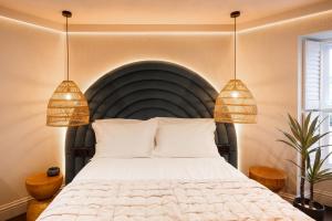 a bedroom with a large bed with two pendant lights at Hive Townhouse in Aberaeron