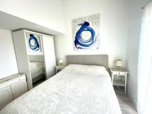 a white bedroom with a bed and a mirror at Apartments Maria in Umag