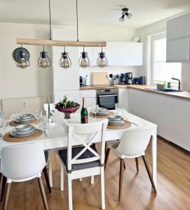 - une cuisine blanche avec une table et des chaises blanches dans l'établissement AusZeit - a75482, à Grömitz