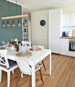 - une table à manger blanche avec des chaises blanches dans la cuisine dans l'établissement AusZeit - a75482, à Grömitz