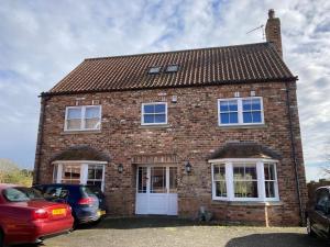 a brick house with cars parked in front of it at Private room Bishop Norton in Market Rasen