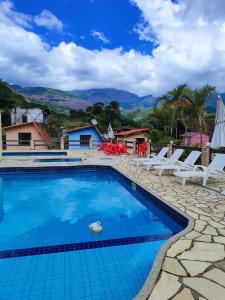 a swimming pool with chairs and mountains in the background at Fazenda Jorge Tardin in Barra Alegre