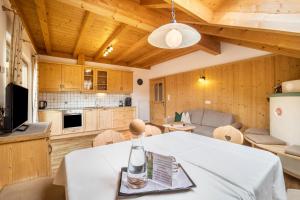 Il dispose d'une cuisine et d'un salon avec une table et des chaises blanches. dans l'établissement Stoffnerhof Apt Alpenrose, à Monguelfo-Tesido