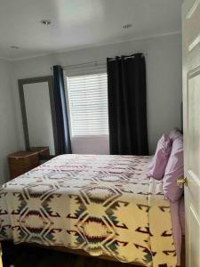 um quarto com uma cama com um edredão e uma janela em An Amazing comfortable home front house em Los Angeles