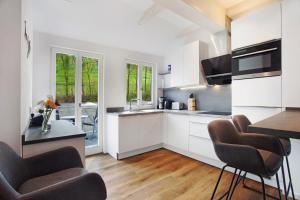 a kitchen with white cabinets and a table and chairs at Gut Vasbach Ferienwohnungen in Kirchhundem