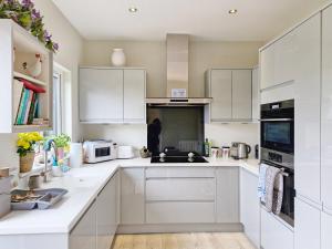 a white kitchen with white cabinets and a sink at The Shed - Pulborough in Pulborough