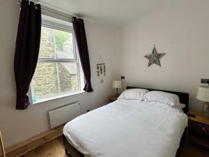 a bedroom with a white bed and a window at Flat 2, Ty Newydd in Barmouth