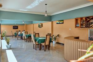 Benru Suites Hotel في كامبالا: مطعم بالطاولات والكراسي والناس جالسين عندهم