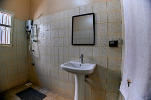 Benru Suites Hotel في كامبالا: حمام مع حوض ومرآة على الحائط