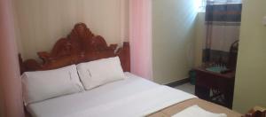 a bedroom with a white bed with a wooden headboard at Green Sea Hotel in Kalangala