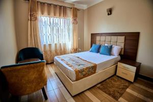 Benru Suites Hotel في كامبالا: غرفة نوم بسرير وكرسي ونافذة
