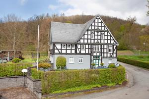ein Schwarz-Weiß-Haus mit Auffahrt in der Unterkunft Gut Vasbach Ferienwohnungen in Kirchhundem