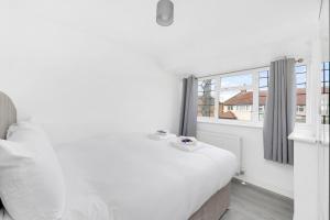 una camera bianca con un letto e una finestra di Pass the Keys Beautiful spacious 7 bed a Hornchurch