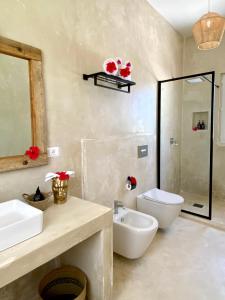 a bathroom with two sinks and a toilet and a shower at Lions Grand SUITE Ocean Front Beach & Pool in Bunju